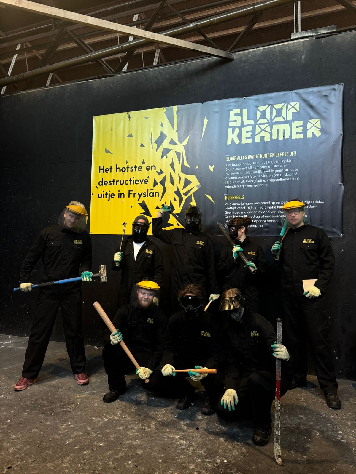 Groep bezoekers met hamers en beschermende kleding voor de Sloopkamer banner